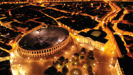 Aerial drone night shot from iconic illuminated Arena theatre and City Hall in Bra square of...