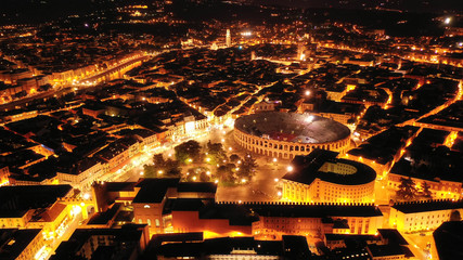 Aerial drone night shot from iconic illuminated Arena theatre and City Hall in Bra square of beautiful city of Verona, Lombardy, Italy
