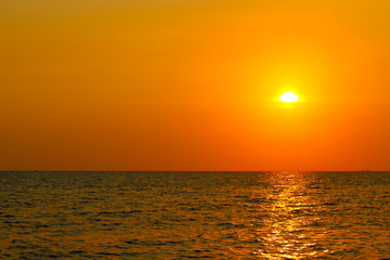 Bright sunset with large yellow sun above the sea surface. Last colors the day. Summer vacation and nature travel is adventure concept background.