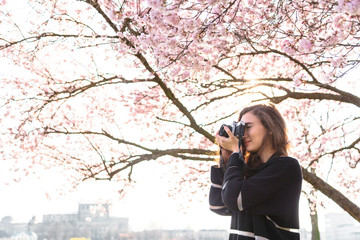 Girl makes picture while standing under tree