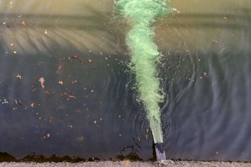 Dirty green chemical polluted water flows into the river, the lake, the sea from the pipe. Top view. Environmental pollution, ecological catastrophe. - 264990465
