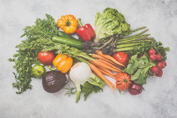 Fresh raw vegetables arrangement cabbage carrots broccoli asparagus pepper fennel tomatoes salad on off white background, top view, toned, selective focus