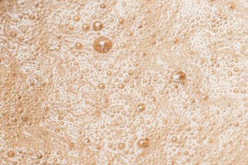 foam on coffee with milk close-up in macro of air bubbles after chipping milk or cream with a glare from lighting