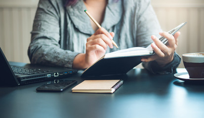 Closeup of hand businesswoman holding notebook and writing to make an appointment