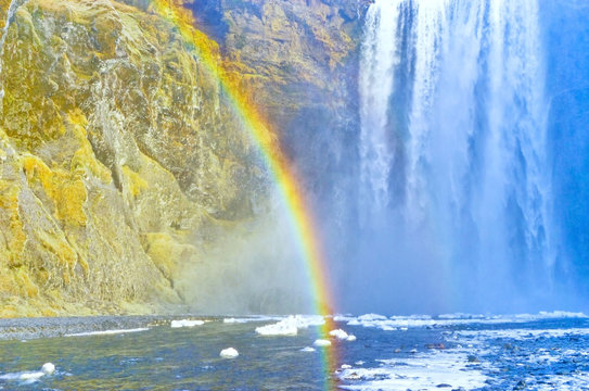 View of Skogafoss waterfall with beautiful rainbow on a sunny day in winter in Iceland.