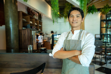 Handsome man barista is working in coffee shop. Waiter serving tea at restaurant