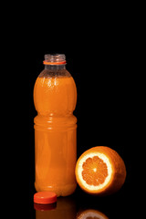 Bottle with fresh orange juice and orange on a black background