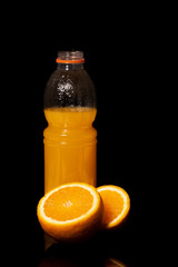 Bottle with fresh orange juice and orange on a black background