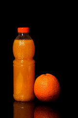 Bottle with fresh orange juice and orange on a black background