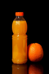 Bottle with fresh orange juice and orange on a black background