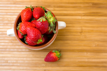 Fresh juicy strawberries in a bowl on a bamboo mat. Close-up image.