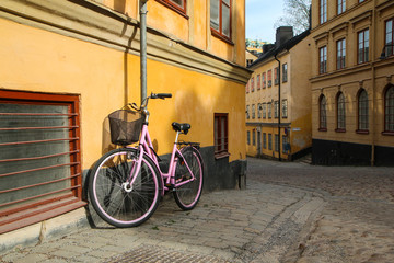 A picture of a lonely pink bike standing in the typical street in Stockholm. The bike looks to be...