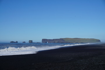 Breathtaking Reynisfjara beach with rocks and blue sky on Iceland in summer