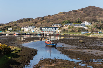 Fototapeta na wymiar Pier with buildings and boat in a low tide Clifden bay
