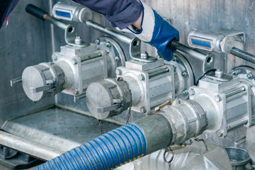 Worker draining the fuel to tank at gas station.