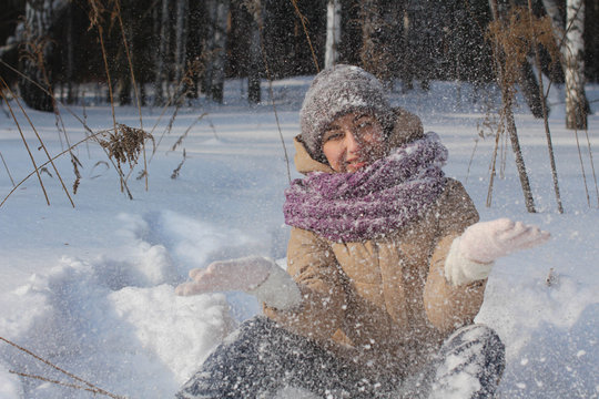 A contented Caucasian woman walks in a winter park. Young woman against a snow-covered park on a sunny day