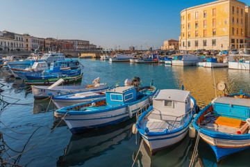 Fototapeta na wymiar Fishing boats on water in the bay of Ortigia island in Syracuse, Sicily, south Italy 