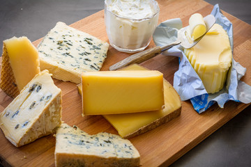 Cheese platter with different cheese, butter and yogurt on wooden board