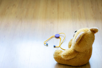 brown toy soft bear with phonendoscope on brown background childhood concept