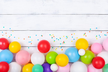 Colorful balloons and confetti on white table top view. Festive or party background. Flat lay....
