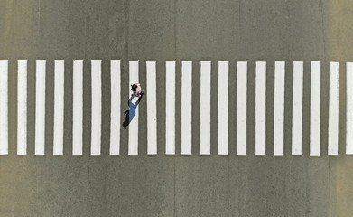 One pedestrian crossing zebra crosswalk, aerial, top view