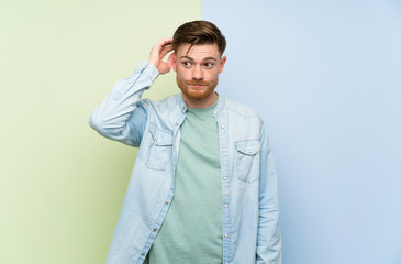Redhead man over colorful background with an expression of frustration and not understanding