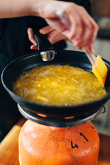 Female chef making omelette on a gas stove