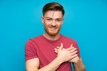 Redhead man on isolated blue wall in love