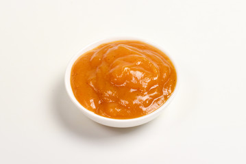 Orange sauce in white plate on white background.