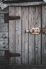 Old wooden door and rusty deadbolt in a small barn