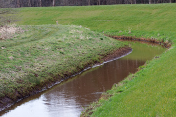 blick auf den mit wasser gefüllten graben zwischen grasflächen in rhede ems emsland deutschland...