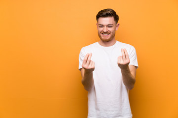 Redhead man over brown wall making money gesture