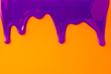 Purple paint leaking down orange background. Close up.