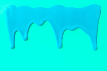 Blue paint leaking down trendy cyan background. Close up.