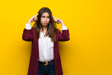 Young woman over yellow wall having doubts and thinking