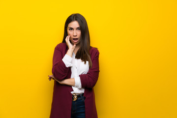 Young woman over yellow wall surprised and shocked while looking right