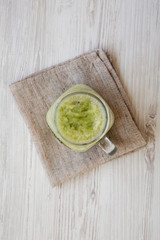 Green celery smoothie in a glass jar over white wooden background. Overhead, flat lay, from above.