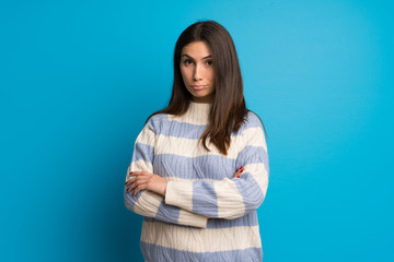 Young woman over blue wall with sad and depressed expression