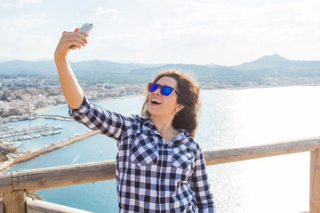 Travel, vacation and holiday concept - Young woman having fun, taking selfie, crazy emotional face and laughing.