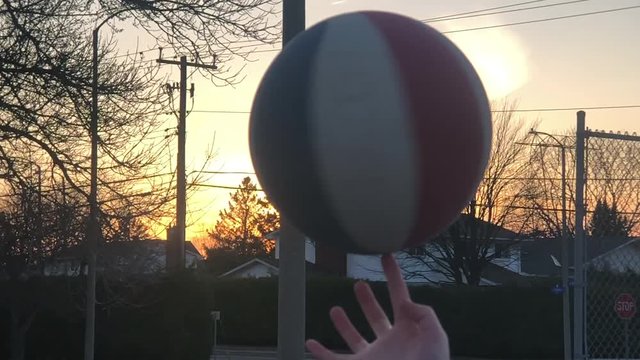 Spinning a basketball on finger at sunset.