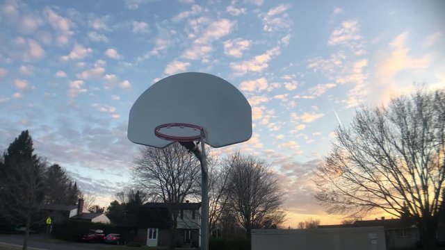 Shooting some hoops at an outdoor basketball court at sunset.