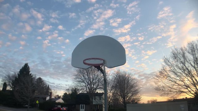 Funny zoom in on basketball going into net at sunset.
