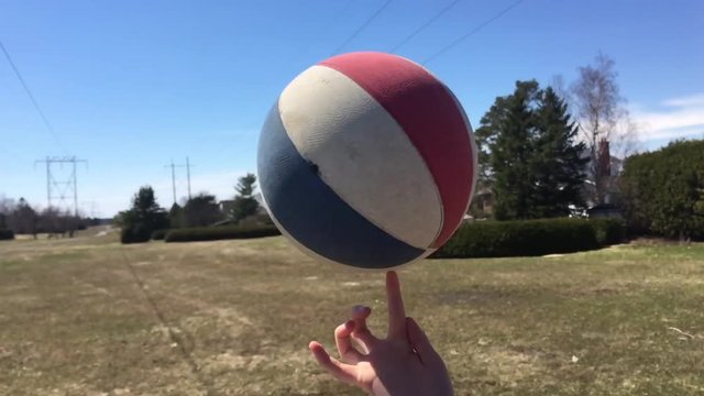 Spinning red, white and blue basketball on finger on a sunny day.