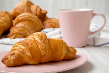 Fresh croissant on a pink plate, side view. Closeup.