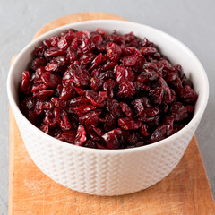Dried cranberries in a bowl over gray background, side view. Close-up.