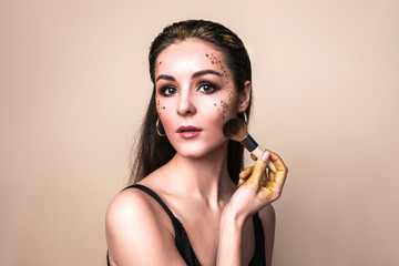 Attractive young woman with glitter make-up and brush.