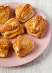 Homemade cottage cheese biscuits on a pink plate over white wooden surface, low angle view. Close-up.