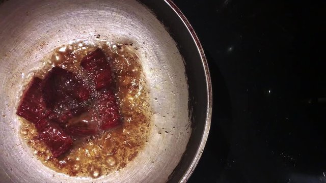 Deep fried chunk beef in very hot oil top view shot cooking with old fry pan