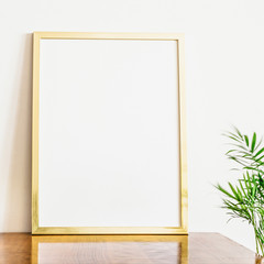 Gold poster frame mockup and a plant.