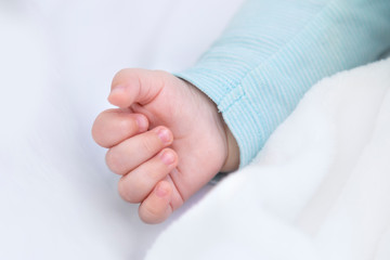 Hand detail of a baby sleeping in a cradle.